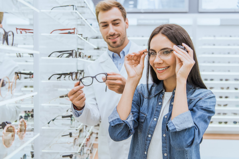 Opticien et une cliente qui essaye des lunettes