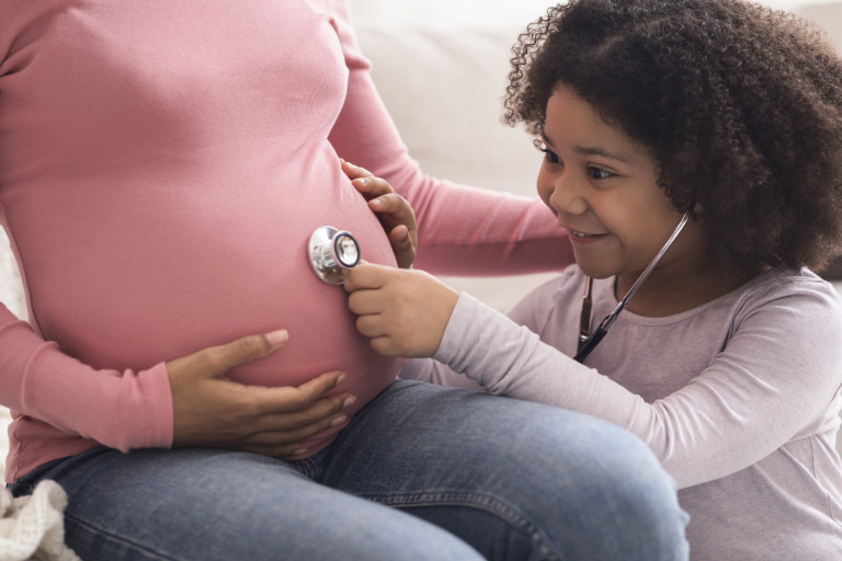 Fille avec stéthoscope sur le ventre de sa maman enceinte