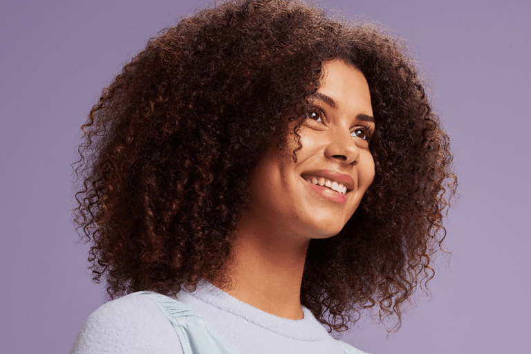 Vrouw met krulhaar lach paarse achtergrond