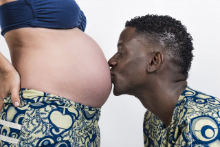 Vader geeft kus op zwangere buik