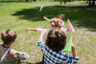 Kinderen spelen buiten en gooien met papieren vliegtuigjes