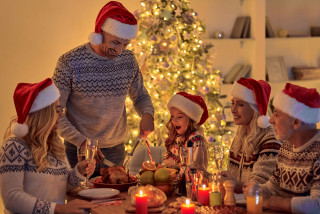 Gezin rond tafel met een kerstboom op de achtergrond