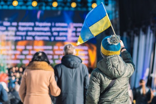 Un enfant avec un drapeau ukrainien regarde la scène