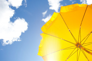 gele parasol voor blauwe lucht met wolken