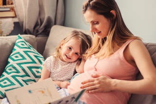 Zwangere vrouw met peuter zit in zetel