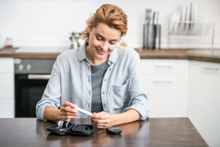 une femme mesure son taux de glycémie dans la cuisine 