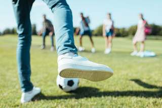 Voet met voetbal gaat trappen naar tieners op een rij