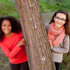 twee glimlachende meisjes tegen boom