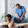 Mannelijke osteopaat behandelt rug van man